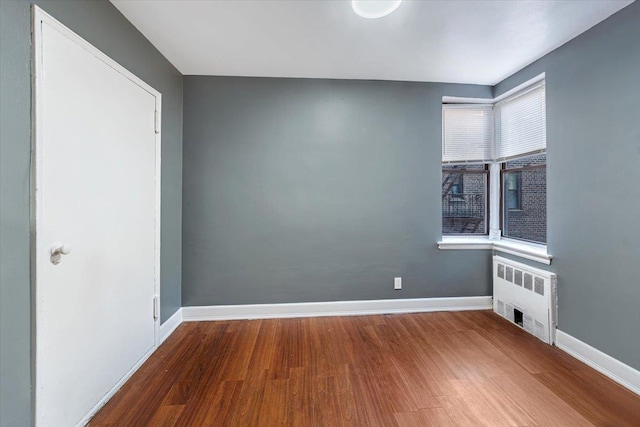 empty room featuring radiator heating unit and wood-type flooring