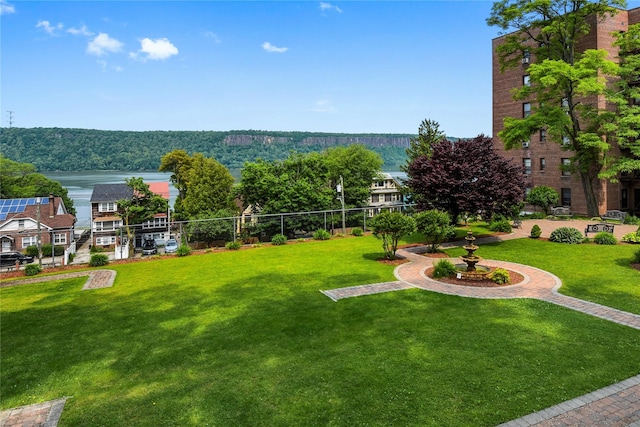 view of property's community with a lawn and a water view