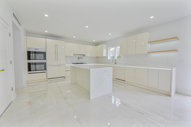 kitchen with a center island, decorative backsplash, white cabinetry, stovetop, and stainless steel double oven