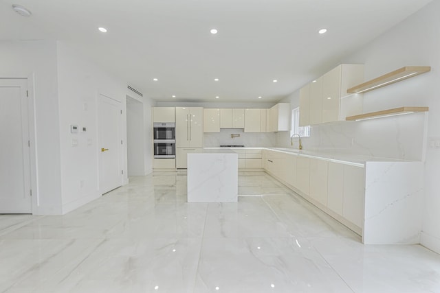 kitchen featuring a center island, decorative backsplash, sink, light stone countertops, and double oven