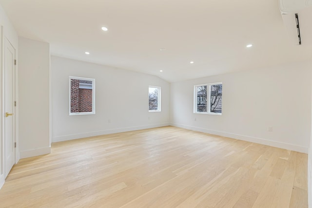 empty room with light hardwood / wood-style floors and lofted ceiling