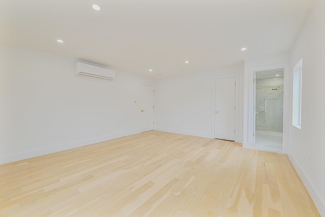 spare room featuring light wood-type flooring and a wall unit AC