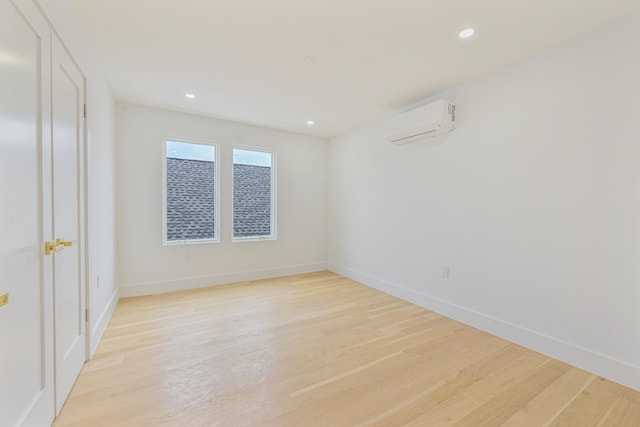 unfurnished room featuring light wood-type flooring and a wall mounted air conditioner