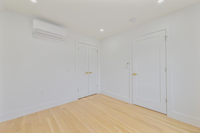 unfurnished room with hardwood / wood-style flooring and an AC wall unit