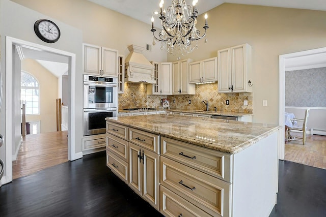 kitchen with pendant lighting, appliances with stainless steel finishes, a kitchen island, custom exhaust hood, and backsplash