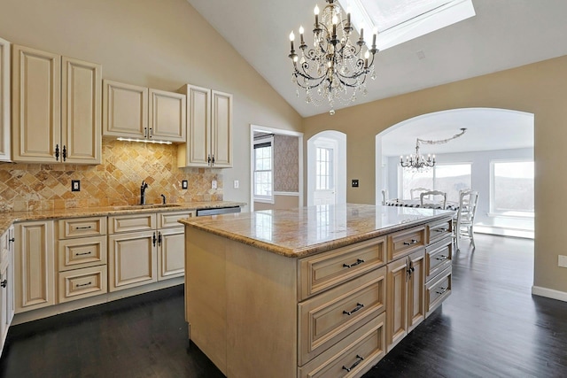 kitchen with a chandelier, hanging light fixtures, sink, a kitchen island, and light stone counters