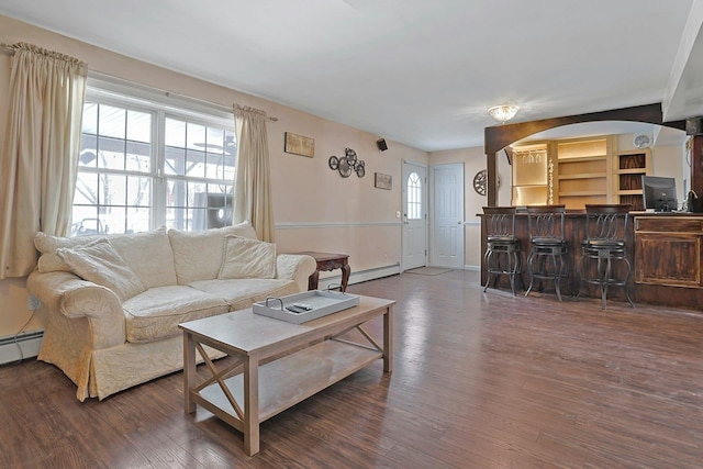 living room featuring indoor bar, a baseboard heating unit, and dark hardwood / wood-style flooring