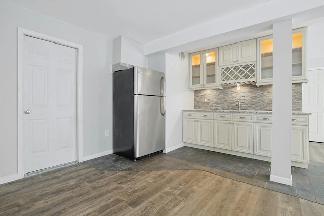 kitchen featuring stainless steel fridge, sink, dark wood-type flooring, light stone countertops, and decorative backsplash