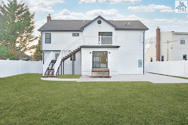 back of property with a yard and a balcony