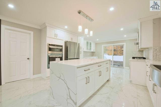 kitchen with decorative backsplash, appliances with stainless steel finishes, white cabinets, a kitchen island, and hanging light fixtures