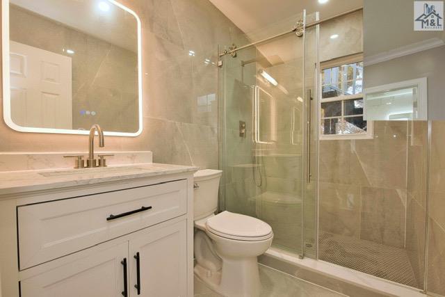 bathroom with vanity, toilet, and a shower with shower door