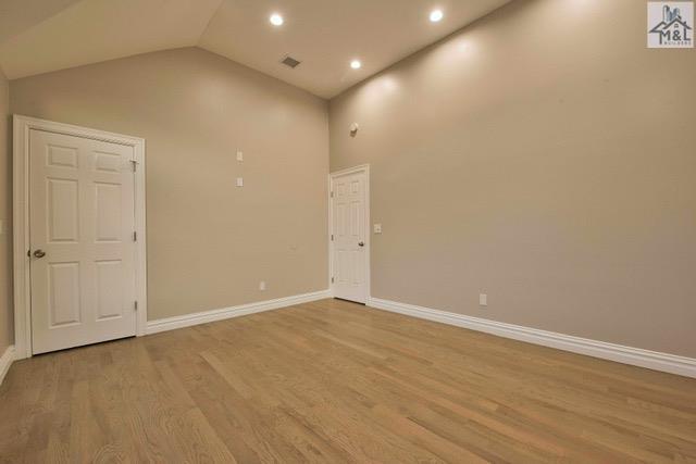 empty room featuring high vaulted ceiling and light hardwood / wood-style flooring