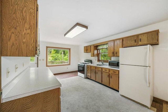 kitchen with light carpet, sink, and white appliances