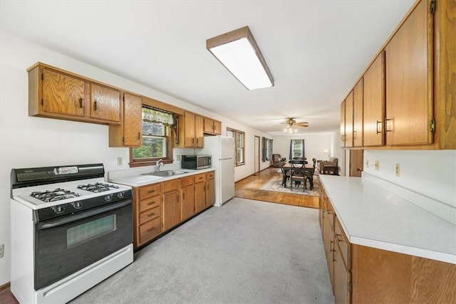 kitchen with white appliances, ceiling fan, and sink