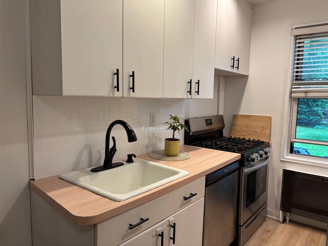 2295 Palmer Ave Unit 1P, New Rochelle, NY 10801 - kitchen featuring appliances with stainless steel finishes, a sink, tasteful backsplash, white cabinetry, and butcher block countertops