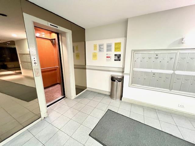 hallway with mail area, baseboards, and light tile patterned flooring