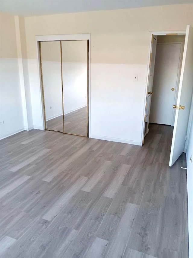 unfurnished bedroom featuring a closet, baseboards, and wood finished floors