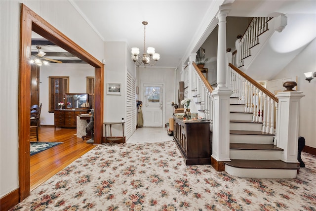 foyer entrance with decorative columns, crown molding, light hardwood / wood-style floors, and a notable chandelier