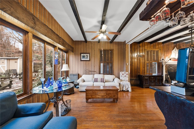 living room with ceiling fan, beamed ceiling, a healthy amount of sunlight, and hardwood / wood-style flooring