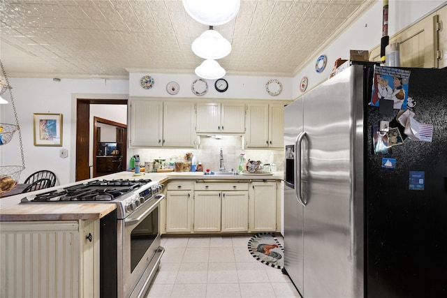 kitchen featuring decorative backsplash, cream cabinetry, stainless steel appliances, and sink