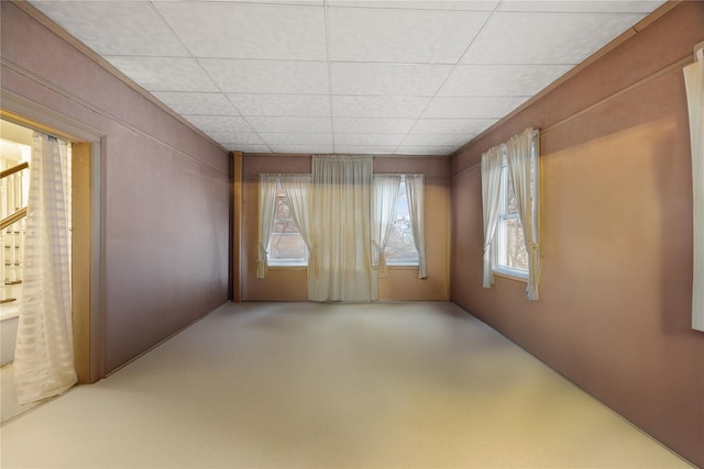 carpeted spare room with a drop ceiling and a healthy amount of sunlight