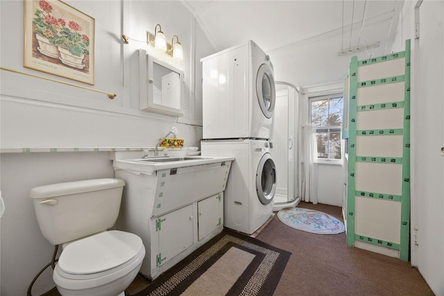 bathroom featuring toilet, vanity, crown molding, and stacked washer and clothes dryer