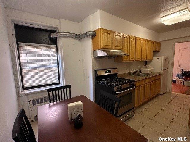 kitchen with gas range, sink, white refrigerator, radiator heating unit, and range hood