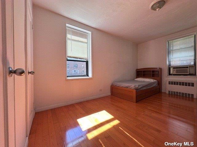 unfurnished bedroom featuring radiator, light hardwood / wood-style flooring, cooling unit, and a textured ceiling