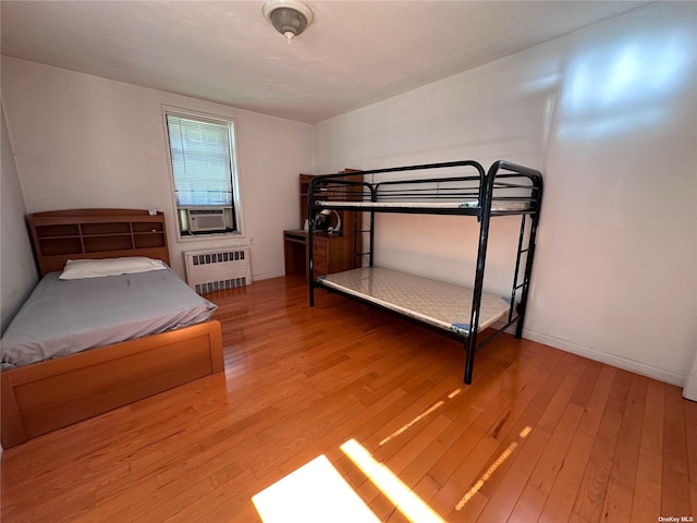 bedroom featuring light hardwood / wood-style flooring, radiator, and cooling unit