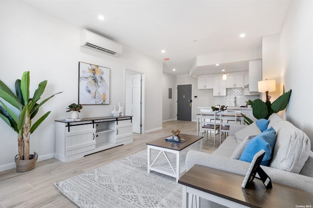 living room with a wall mounted AC, sink, and light wood-type flooring