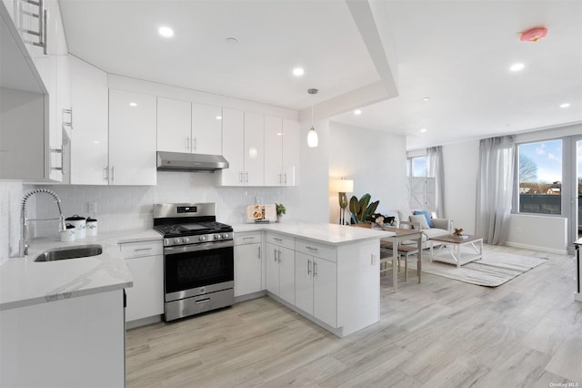 kitchen with white cabinets, sink, decorative light fixtures, gas stove, and kitchen peninsula