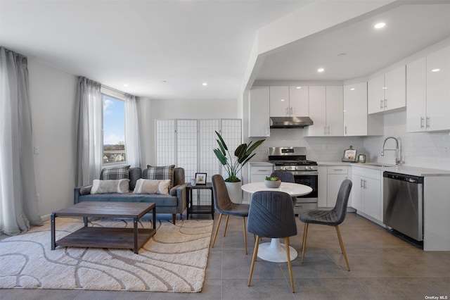 kitchen with tasteful backsplash, stainless steel appliances, under cabinet range hood, white cabinetry, and a sink