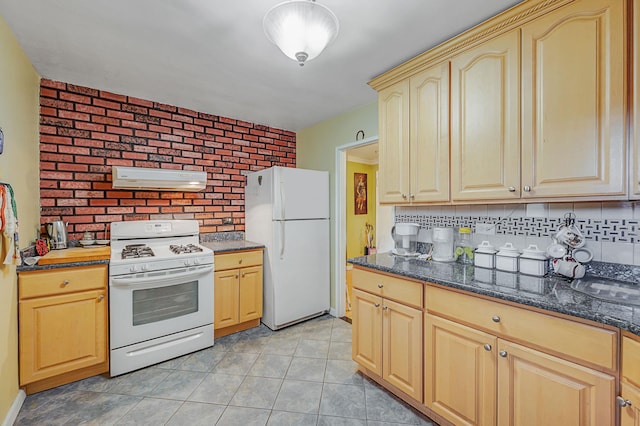 kitchen with brick wall, white appliances, ventilation hood, light brown cabinets, and dark stone countertops