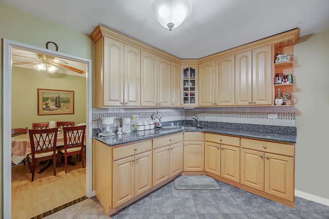 kitchen with ceiling fan, light brown cabinets, sink, tasteful backsplash, and dark stone countertops