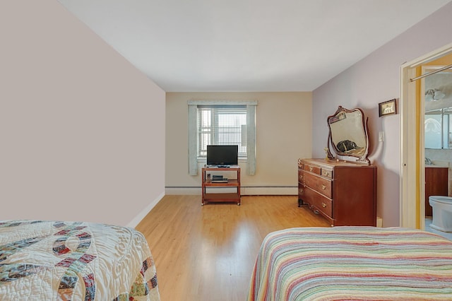 bedroom with connected bathroom, light hardwood / wood-style floors, and baseboard heating