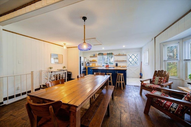 dining area featuring ornamental molding, wooden walls, and dark wood-type flooring