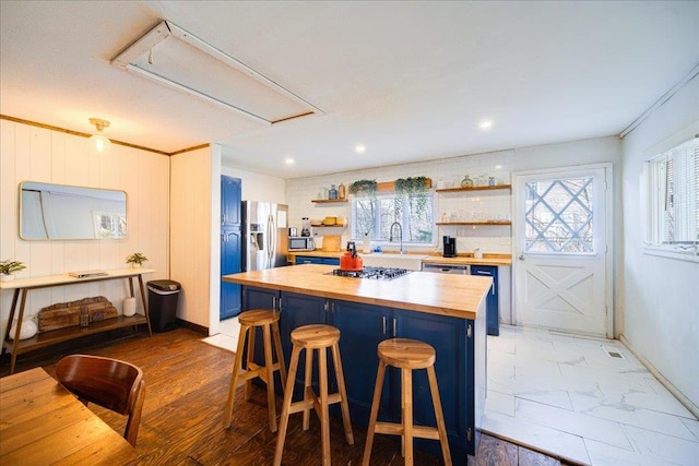 kitchen featuring butcher block countertops, a breakfast bar, a kitchen island, and blue cabinets