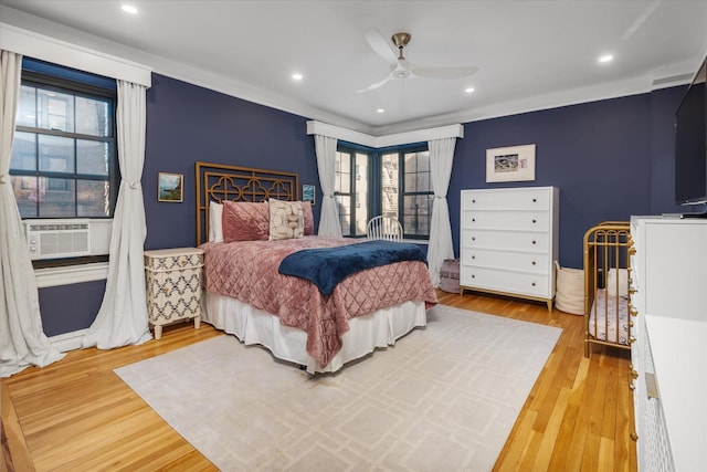 bedroom featuring multiple windows, light wood-type flooring, ceiling fan, and cooling unit