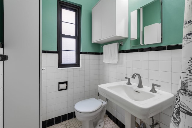 bathroom with toilet, sink, tile walls, and tile patterned flooring