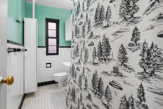 bathroom featuring tile patterned floors, toilet, a shower, and tile walls