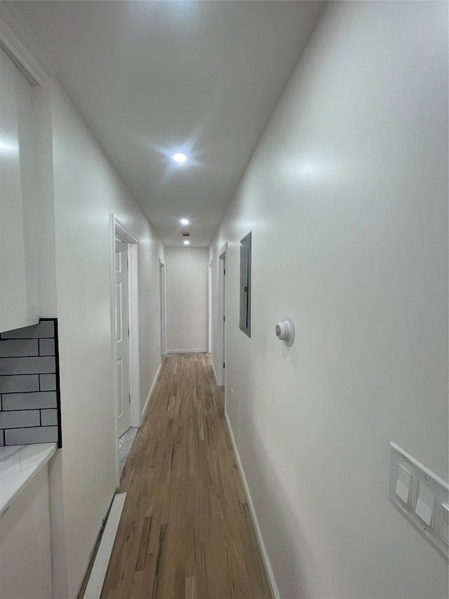 corridor with electric panel and light wood-type flooring