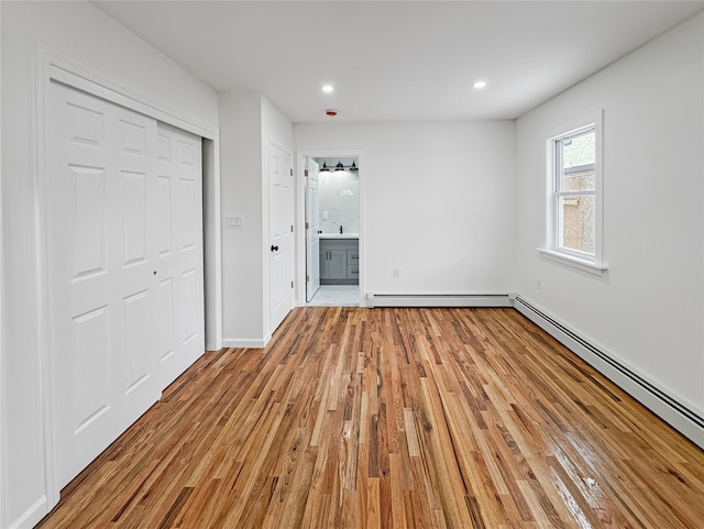 unfurnished bedroom with a baseboard radiator, connected bathroom, a closet, and light hardwood / wood-style flooring