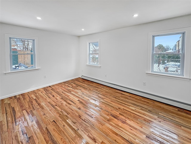 unfurnished room featuring light hardwood / wood-style floors and a baseboard heating unit