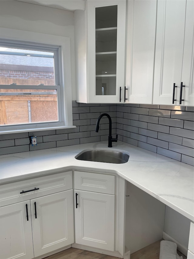 kitchen featuring white cabinetry, light stone countertops, sink, and decorative backsplash