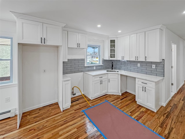 kitchen with white cabinetry, sink, light hardwood / wood-style floors, and decorative backsplash