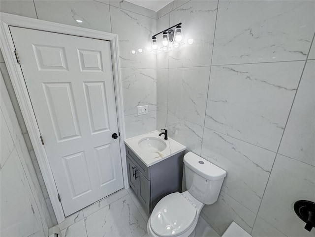 bathroom with vanity, toilet, and tile walls