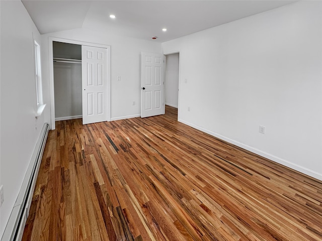 unfurnished bedroom featuring hardwood / wood-style flooring, a closet, and baseboard heating