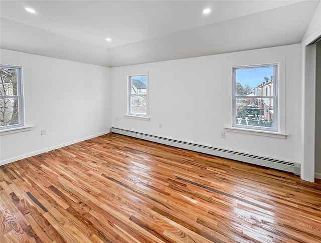 spare room featuring lofted ceiling, light hardwood / wood-style flooring, and a baseboard heating unit