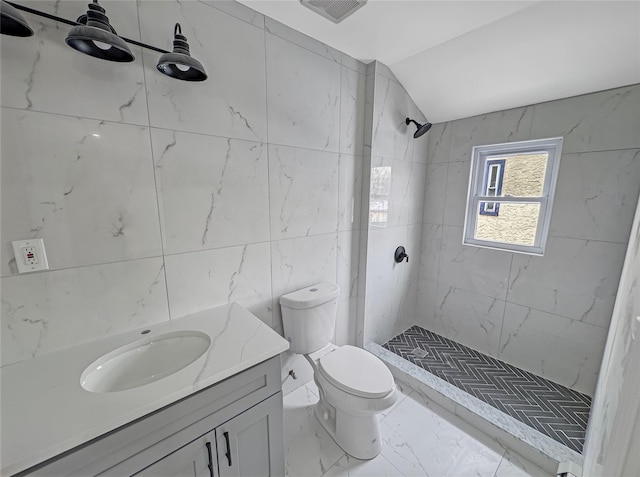 bathroom with vaulted ceiling, tile walls, vanity, tiled shower, and toilet