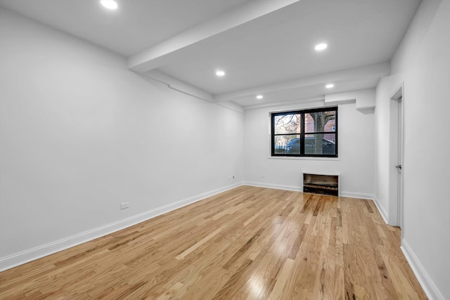 unfurnished living room with light hardwood / wood-style floors and beam ceiling